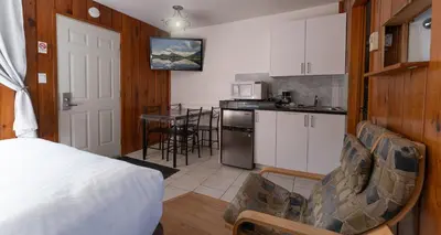 a room with a bed and a kitchen with a counter at Cedar Motel in Radium Hot Springs
