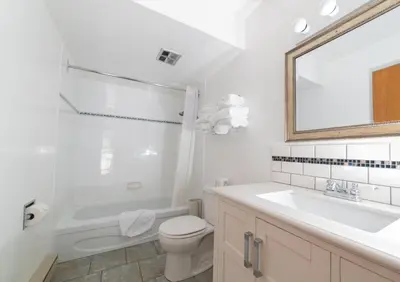 a white bathroom with a sink toilet and a mirror at Cedar Motel in Radium Hot Springs