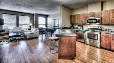 a large kitchen with wooden cabinets and a living room at Grand Inn & Residence- Grande Prairie in Grande Prairie