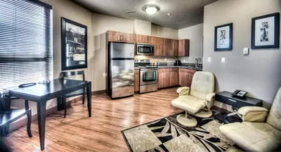 a living room with a table and a kitchen at Grand Inn & Residence- Grande Prairie in Grande Prairie