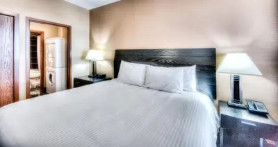 a bedroom with a large white bed and two lamps at Grand Inn & Residence- Grande Prairie in Grande Prairie