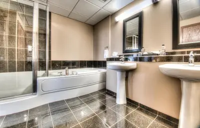 a bathroom with two sinks and a bath tub and a sink at Grand Inn & Residence- Grande Prairie in Grande Prairie
