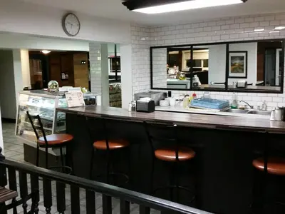 a bar in a restaurant with a counter and stools at Wild Rose Country Inn in Grande Prairie