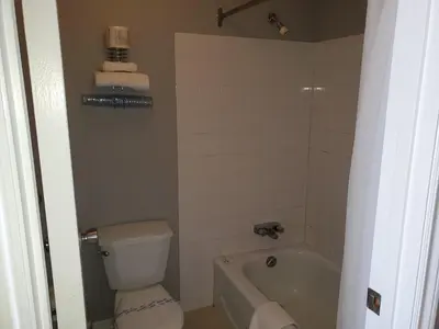 a bathroom with a toilet and a tub and a sink at Wild Rose Country Inn in Grande Prairie