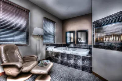 a bathroom with a chair and a bath tub and a chair at Podollan Inn & Spa - Grande Prairie in Grande Prairie
