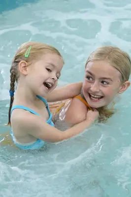 two young girls are swimming in a pool at St. Albert Inn & Suites in St. Albert