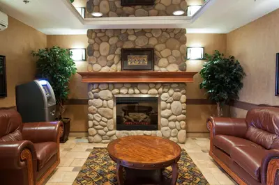 a living room with a fireplace and leather furniture at Days Inn & Suites by Wyndham Strathmore in Strathmore