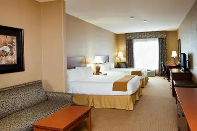 a hotel room with two beds and a couch at Days Inn & Suites by Wyndham Strathmore in Strathmore