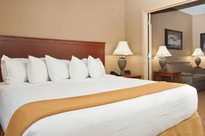 a hotel room with a large bed with white pillows at Days Inn & Suites by Wyndham Strathmore in Strathmore