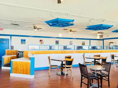 a dining room with tables and chairs and blue umbrellas at Ramada by Wyndham Dawson Creek in Dawson Creek
