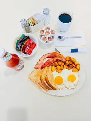 a plate of breakfast food with eggs bacon and toast at Ramada by Wyndham Dawson Creek in Dawson Creek