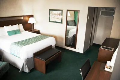 a hotel room with a large bed and a mirror at Ramada by Wyndham in Quesnel