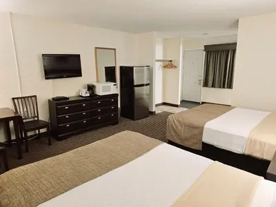 a hotel room with two beds and a flat screen tv at Canadian Motor Inn in Grande Prairie