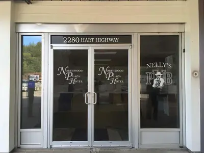 a front door of a store with signs on it at Northwood Plaza Hotel in Prince George