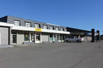 a building with a car parked in a parking lot at Northwood Plaza Hotel in Prince George
