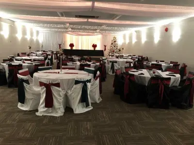 a banquet hall with white tables and a christmas tree at Northwood Plaza Hotel in Prince George