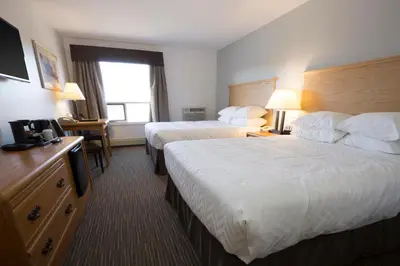 a hotel room with two beds and a television at Tower Inn & Suites in Quesnel