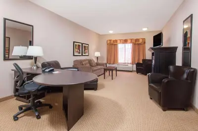 a hotel room with a table and chairs and a living room at Ramada by Wyndham Brooks in Brooks
