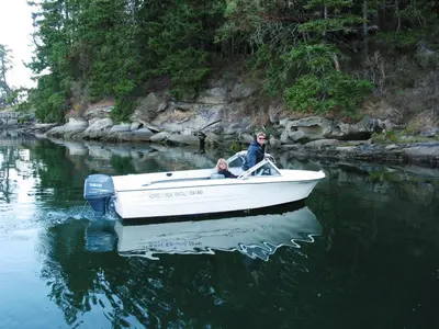 a man and a child in a boat in the water at Sticks and Stones Cottage-Arbutus Grove in Galiano