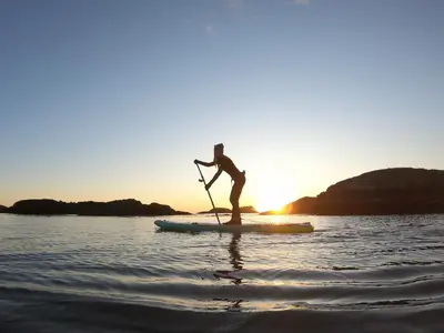 a person standing on a paddle board in the water at Ocean Village Resort in Tofino