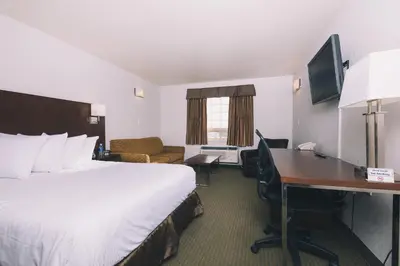 a hotel room with a bed and a desk at Service Plus Inns and Suites in Grande Prairie