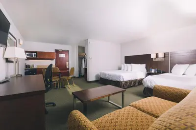 a hotel room with two beds and a table and chairs at Service Plus Inns and Suites in Grande Prairie