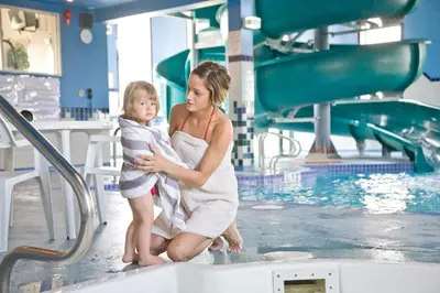 a woman holding a child in front of a swimming pool at Service Plus Inns and Suites in Grande Prairie