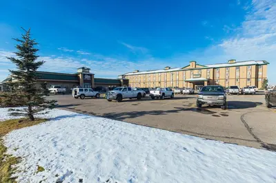 a parking lot with cars parked in front of a building at Service Plus Inns and Suites in Grande Prairie