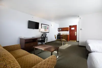 a hotel room with a couch and a desk at Service Plus Inns and Suites in Grande Prairie