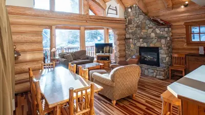 a living room with a stone fireplace in a log cabin at Snow Creek Cabins by Fernie Lodging Co in Fernie