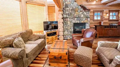 a living room with a couch and a stone fireplace at Snow Creek Cabins by Fernie Lodging Co in Fernie
