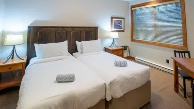a bedroom with two beds and a desk and a window at Timberline Lodges by Fernie Lodging Co in Fernie