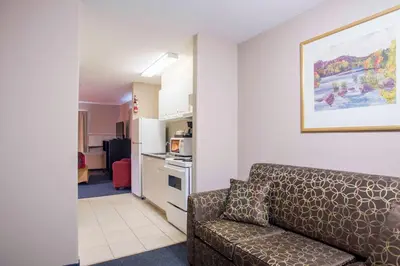 a living room with a couch and a kitchen at Ramada Limited 100 Mile House in One Hundred Mile House