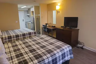 a hotel room with two beds and a flat screen tv at Rodeway Inn & Suites in Kamloops