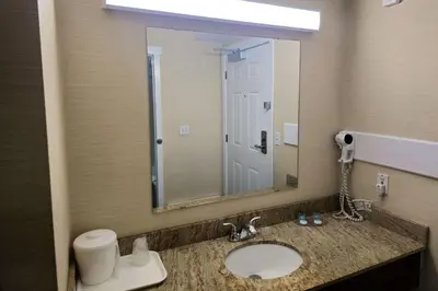 a bathroom with a sink with a mirror and a toilet at Rodeway Inn & Suites in Kamloops