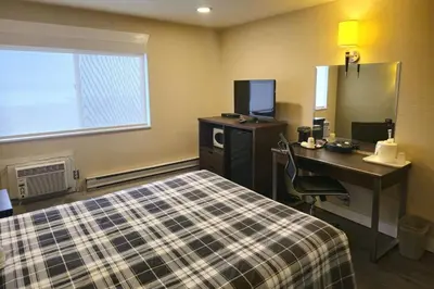 a hotel room with a bed and a desk and a computer at Rodeway Inn & Suites in Kamloops