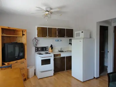 a kitchen with a white refrigerator and a tv at Bella Villa Resort Motel in Osoyoos