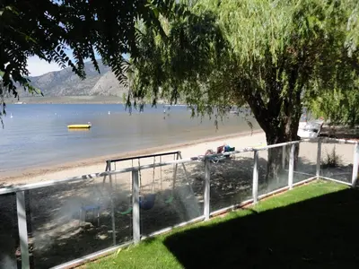 a view of a beach with a tree and a fence at Bella Villa Resort Motel in Osoyoos