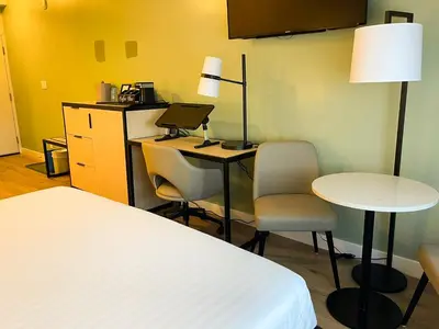 a room with a bed and a desk with a laptop at SKKY Hotel in Whitehorse