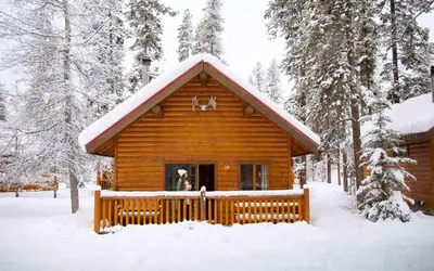 a man standing in a window of a log cabin in the snow at Baker Creek By Basecamp in Lake Louise
