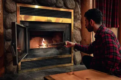 a man is holding a stick in front of a fireplace at Baker Creek By Basecamp in Lake Louise