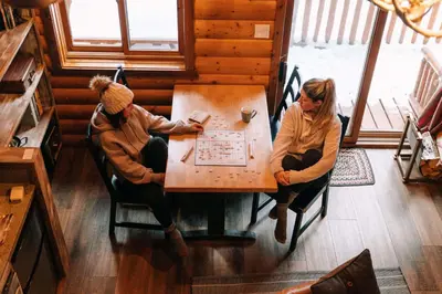 two people sitting at a wooden table in a room at Baker Creek By Basecamp in Lake Louise