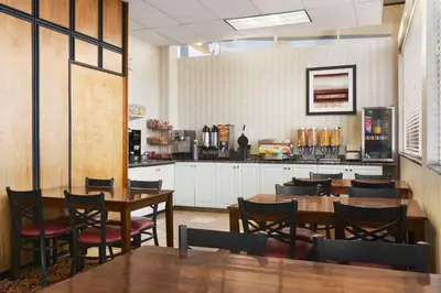 a restaurant with tables and chairs and a kitchen at Travelodge by Wyndham North Battleford in North Battleford