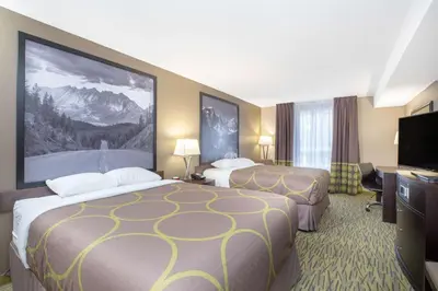 a hotel room with two beds and a flat screen tv at Super 8 by Wyndham Canmore in Canmore
