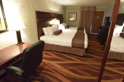 a hotel room with two beds and a desk and a chair at Tropical Inn - North Battleford in North Battleford