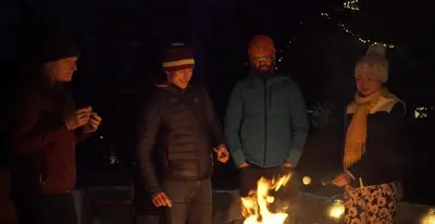a group of people standing around a fire at A Bear and Bison Country Inn in Canmore