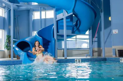 a woman holding a child on a water slide in a pool at Stoney Nakoda Resort & Casino in Seebe
