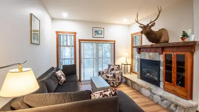 a living room with a fireplace with a deer head on the wall at Snow Creek Lodge by Fernie Lodging Co in Fernie