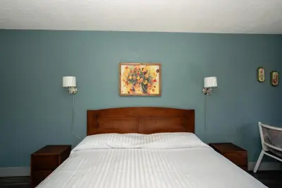 a bedroom with a bed and a painting on the wall at Alpine Inn in Valemount