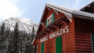 a sign on the side of a building with a snow covered mountain at Paradise Lodge and Bungalows in Lake Louise